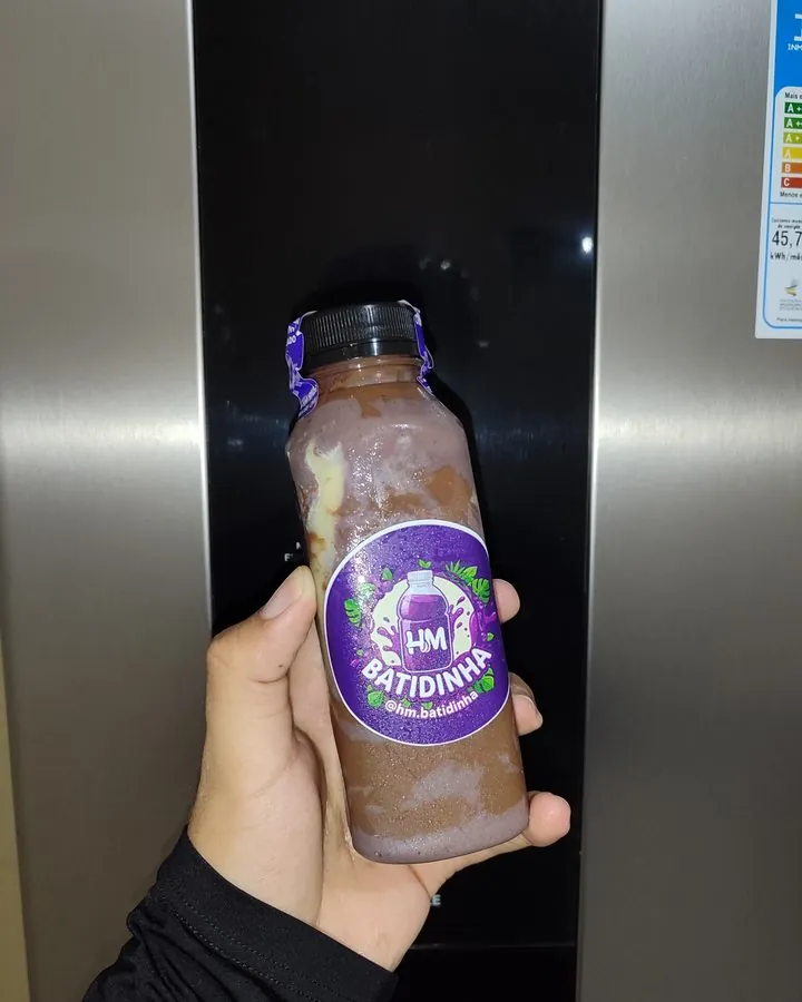 Garrafinha HM Batidinha de açaí com chocolate, segurada na mão (abre o Instagram)
